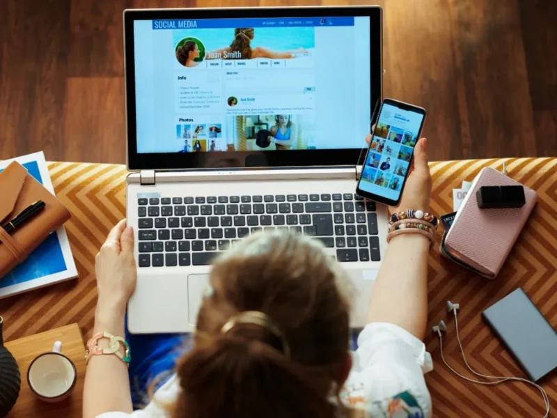 A woman using social media on her laptop and phone.