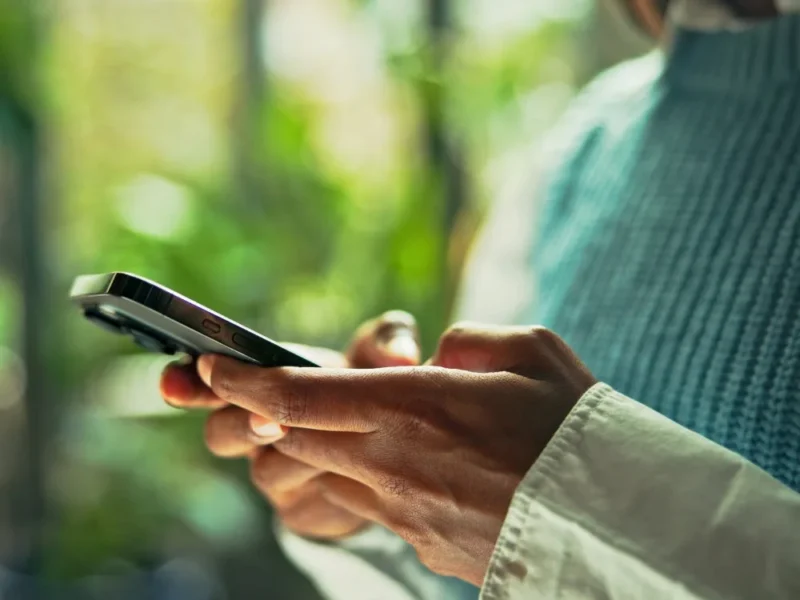 A woman using a smartphone with a green background.