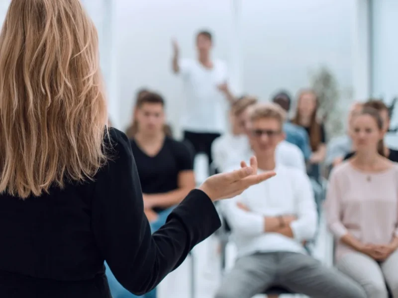 A woman performing a presentation to a full room.