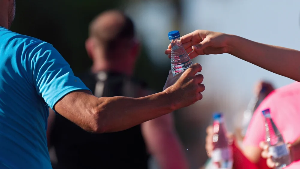 A spectator hands a bottle of water to a marathon runner.