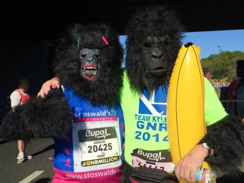 Two marathon runners dressed as gorillas holding an inflatable banana.