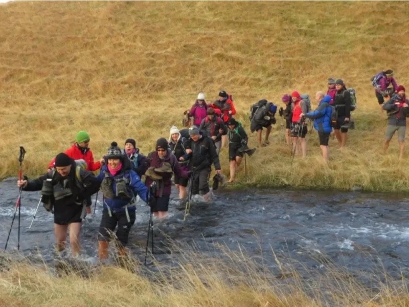 A large group of people crossing a river.