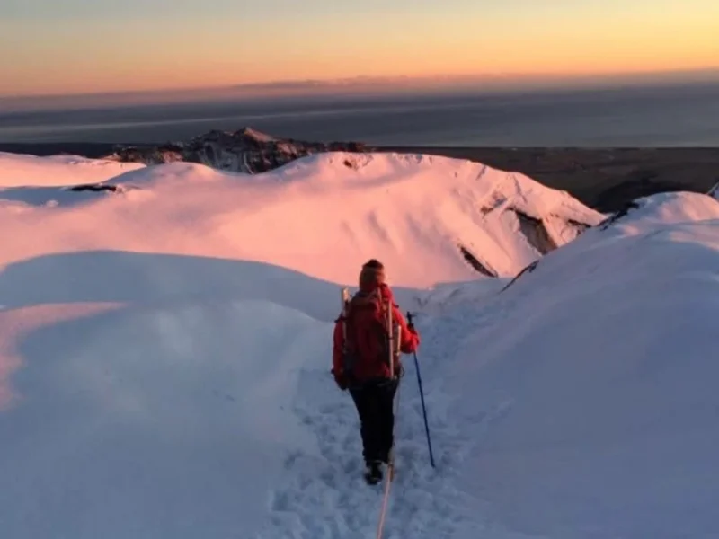 A person hiking in the snow at sunset.