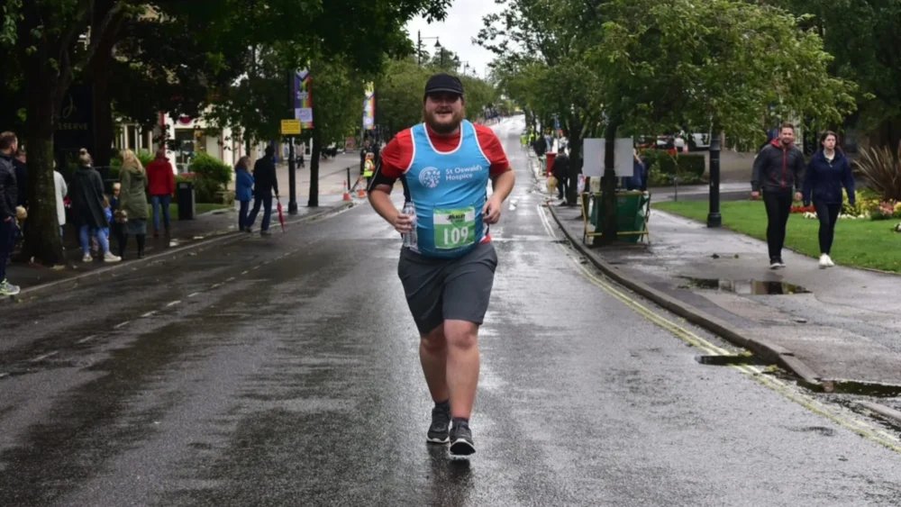 A man running on a rural road in marathon gear.