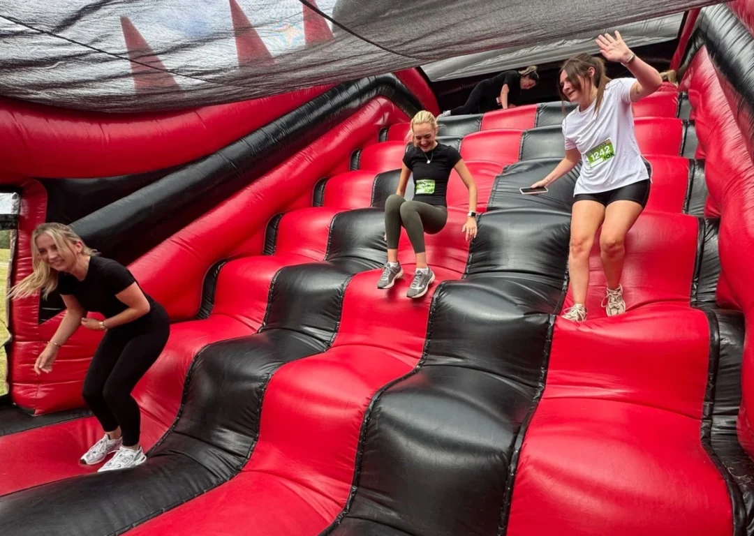 Charity runners on a red and black inflatable obstacle course.
