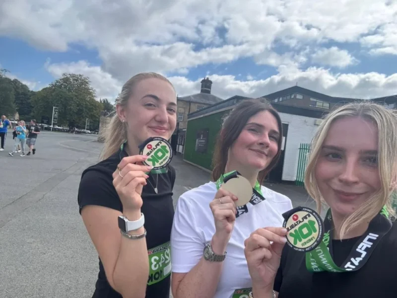 Three runners smiling and holding their medals.