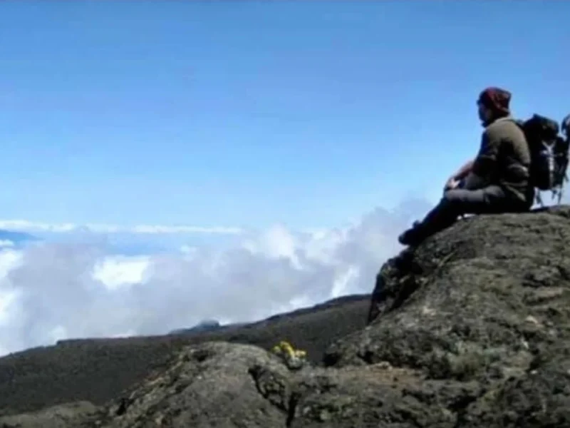 A man sitting alone atop a mountain.