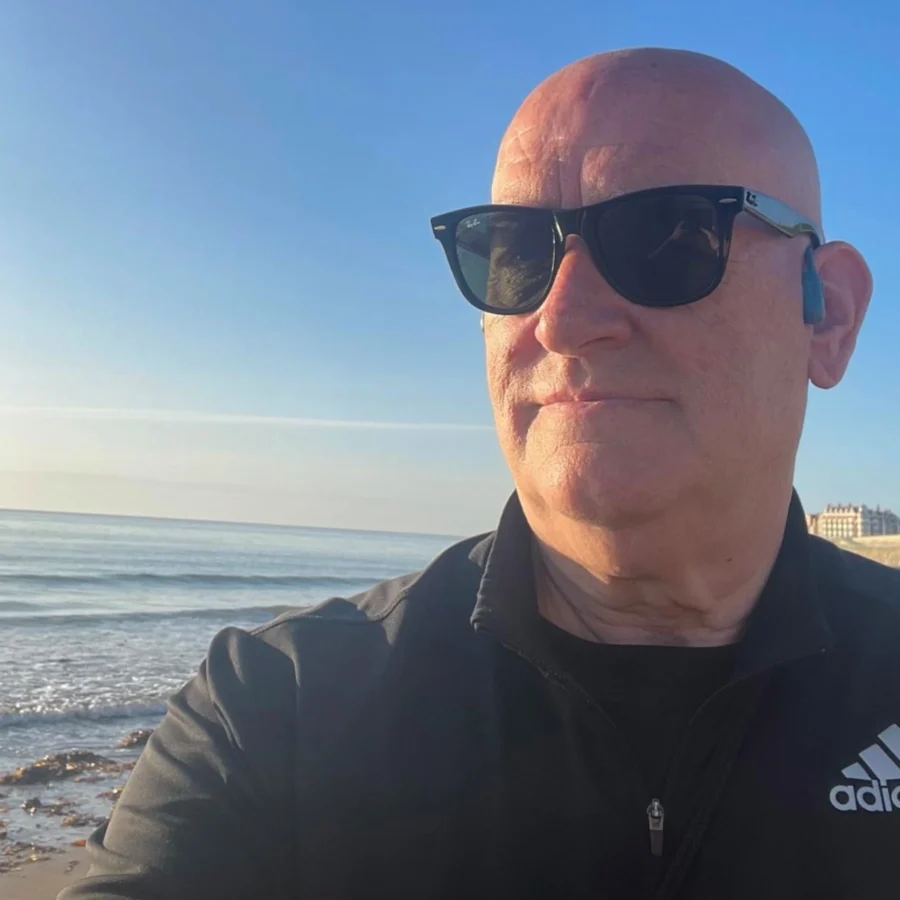 David Banks wearing athleticwear and sunglasses on the beach.