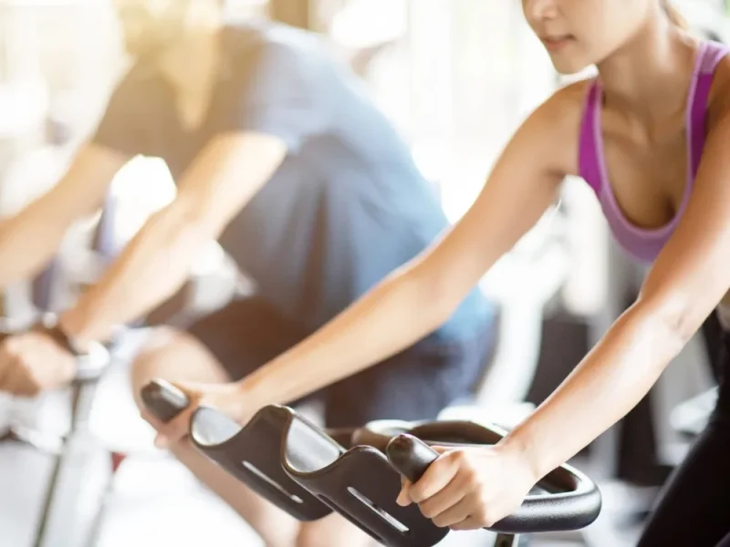 A man and woman using exercise bikes in the gym.