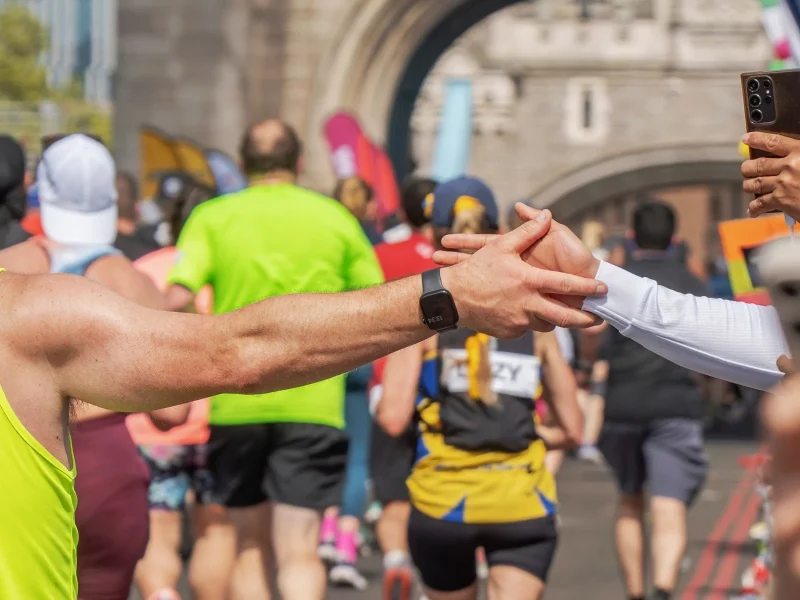 A marathon runner high fives a supporter.